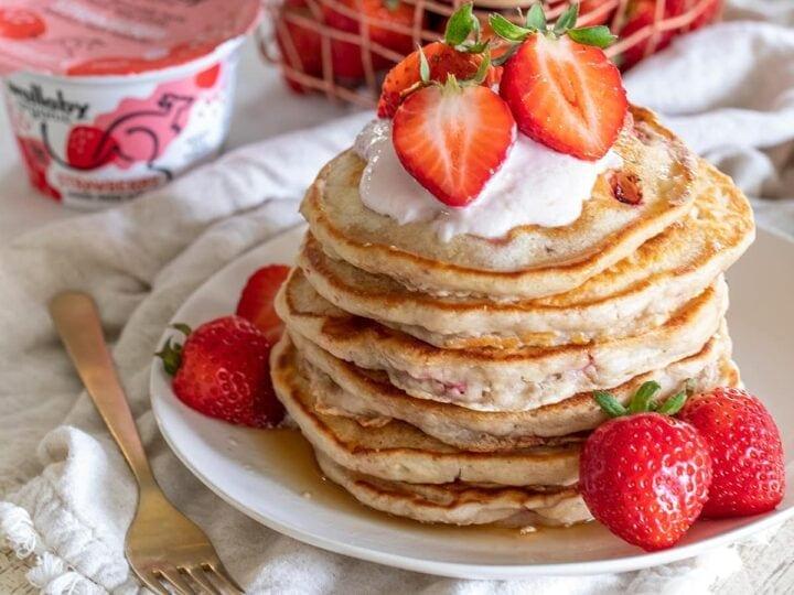 Close up shot of a fluffy strawberry pancake with yogurt and fresh strawberries