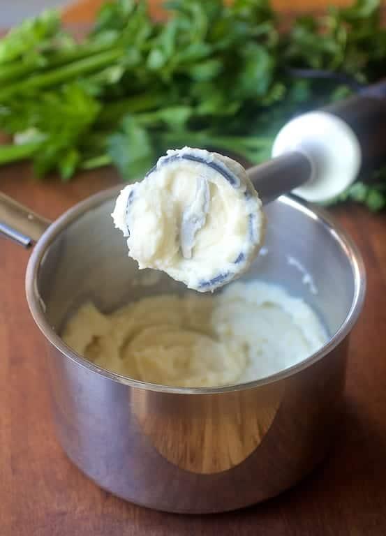 Close-up of callaloo and celery root puree being blended with an immersion blender