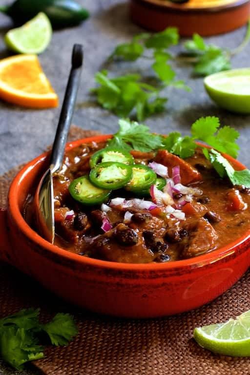 Close-up shot of a vibrant Brazilian Citrus Feijoada in a rustic Dutch oven, garnished with orange slices and cilantro