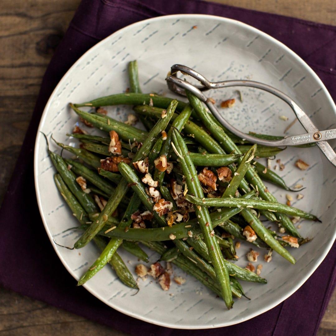 Close-up of roasted green beans with rosemary and garlic, vibrant green color, glistening with oil