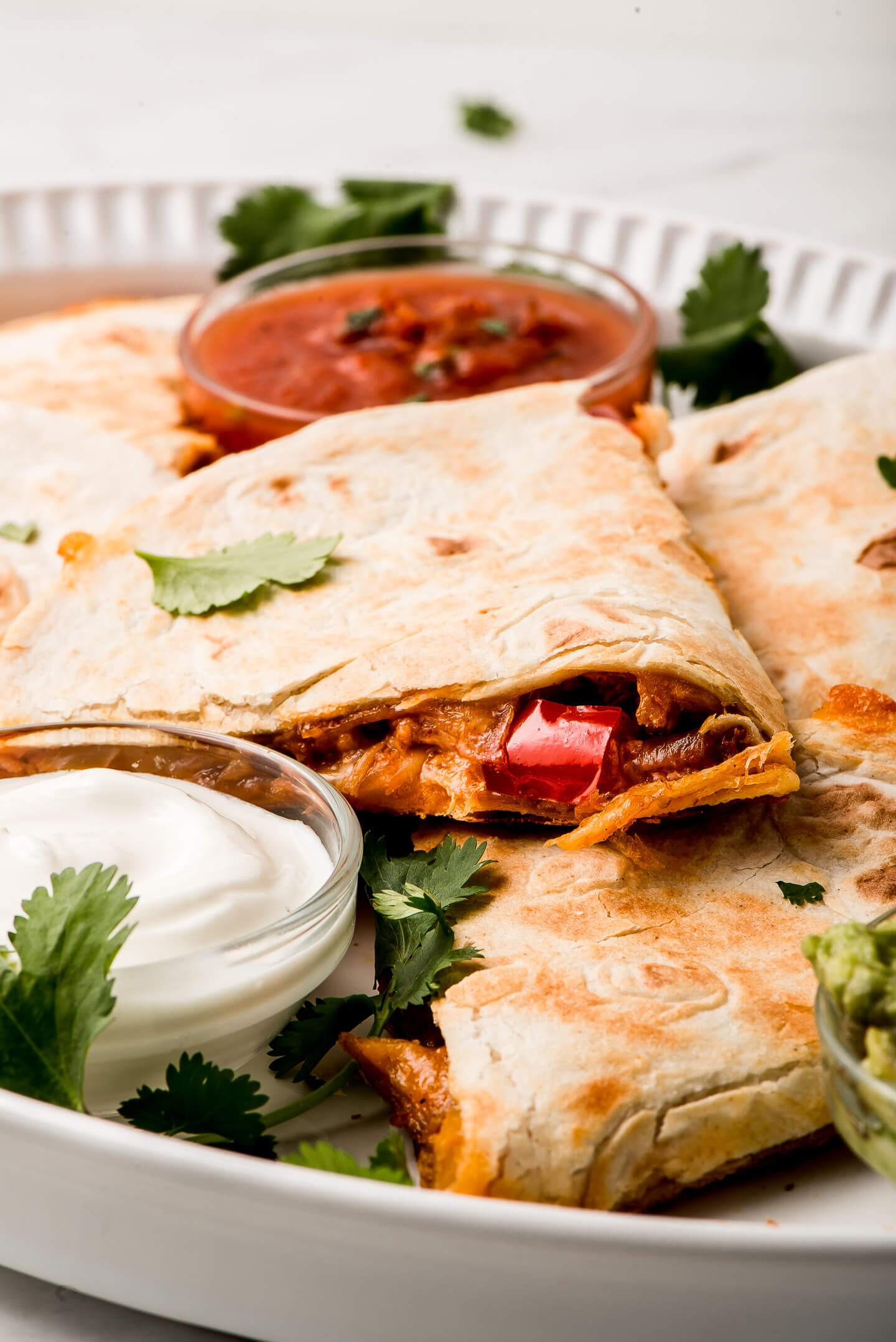 Close-up shot of two delicious chicken quesadillas with salsa on the side, ready to be eaten.