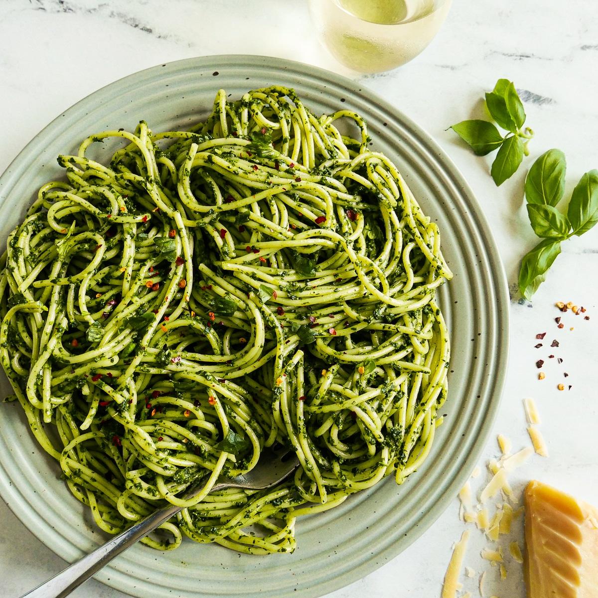 A person enjoying a plate of creamy green pasta