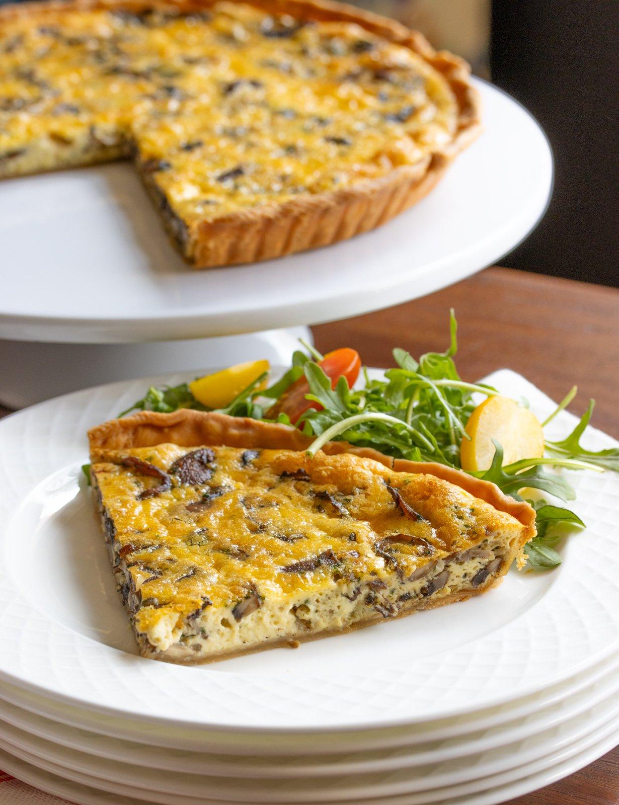 hand slicing a piece of chicken and mushroom quiche
