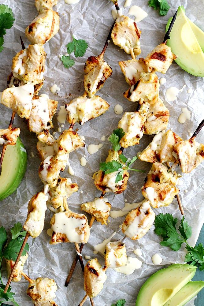 Close-up shot of juicy grilled chicken breast with vibrant green avocado ranch dressing.