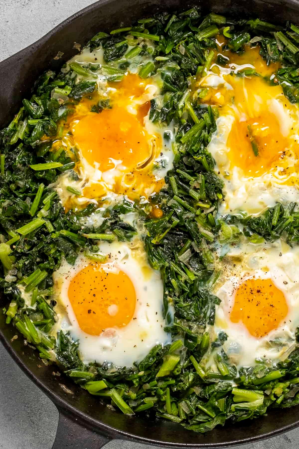 Close-up shot of sautéed eggs with spinach and mozzarella in a pan
