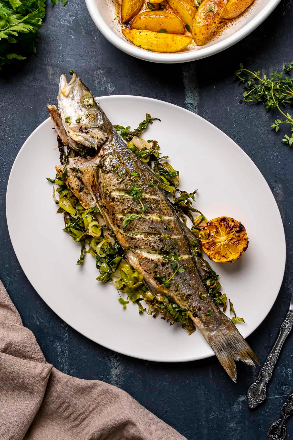 Grilled fish served with a side salad and roasted potatoes