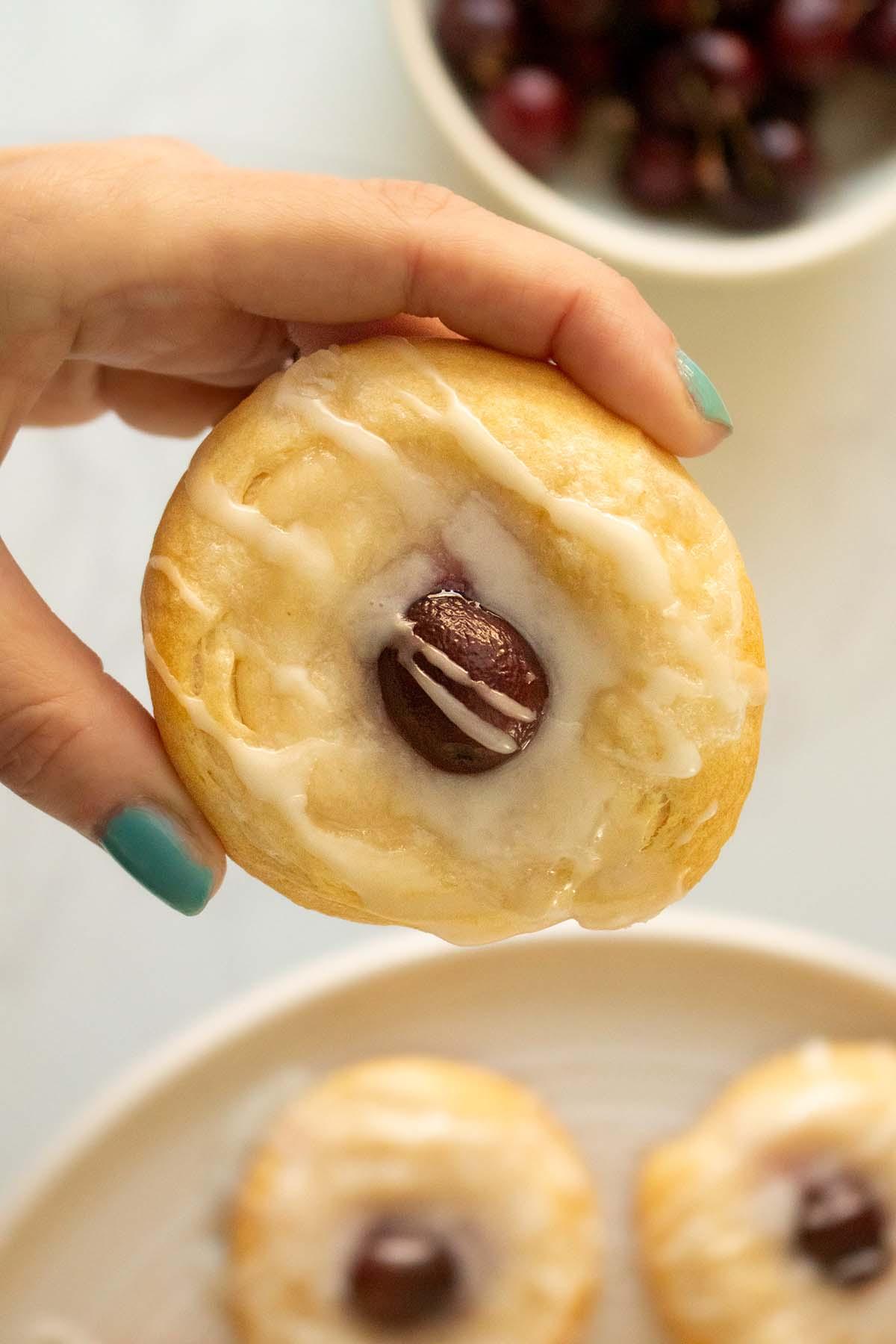 Close up shot of a hand holding a warm, flaky danish