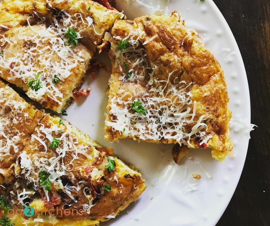 A rustic, close-up shot of golden-brown sun-dried tomato and basil frittatas in an oven-safe skillet, garnished with fresh basil sprigs.