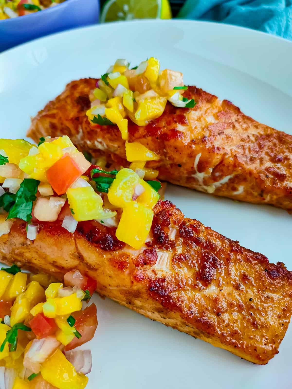 serving of paprika rubbed salmon topped with mango salsa on a plate