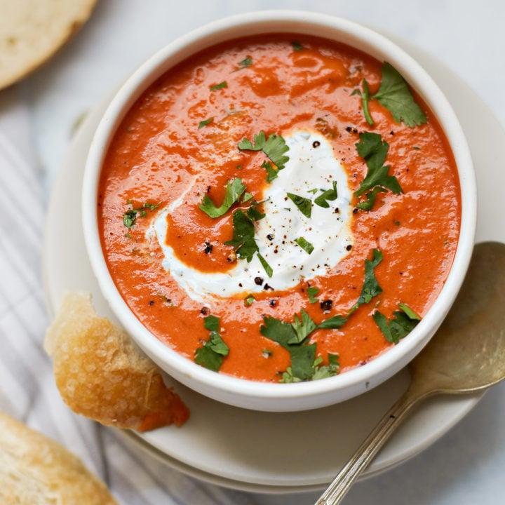 bowl of roasted red pepper and walnut soup with a swirl of cream