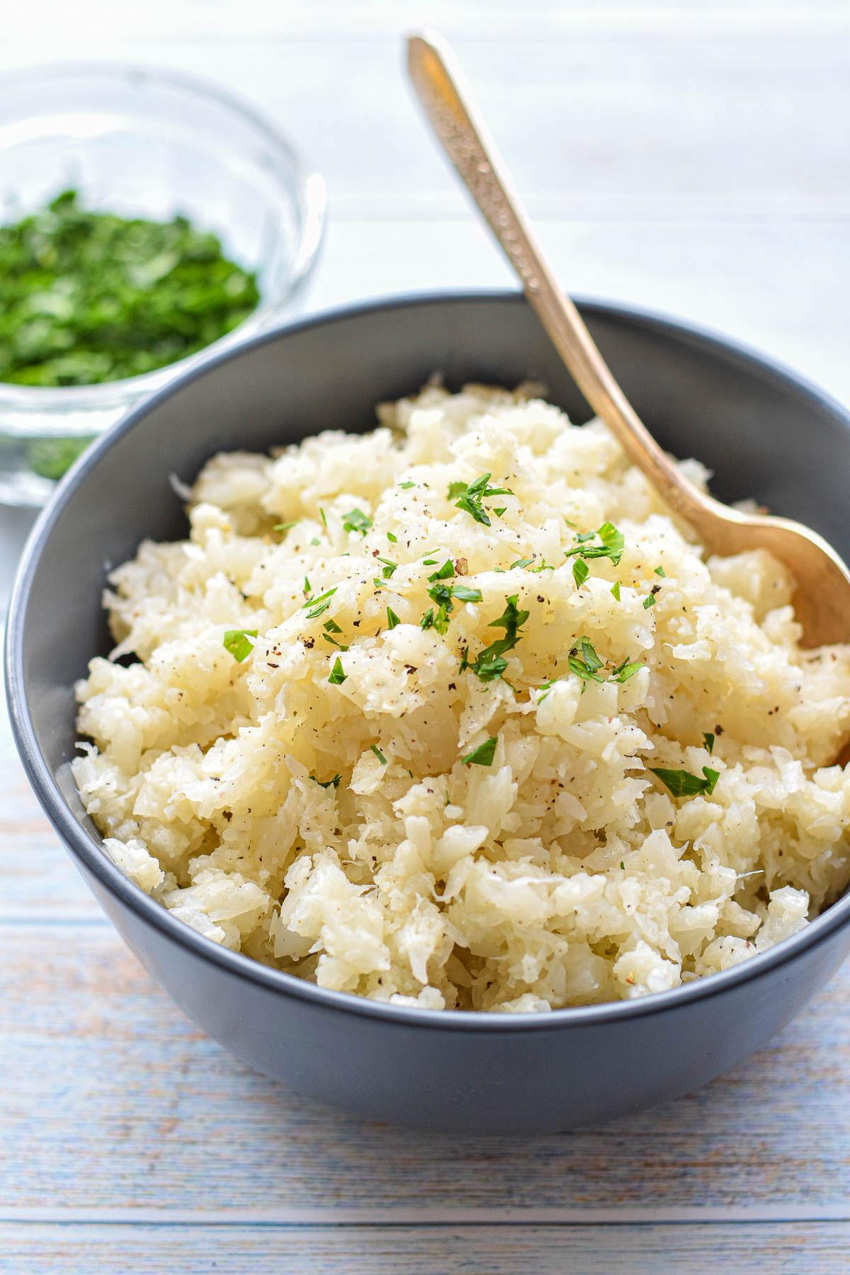 A close-up shot of a person happily enjoying a bowl of the finished cauliflower rice dish