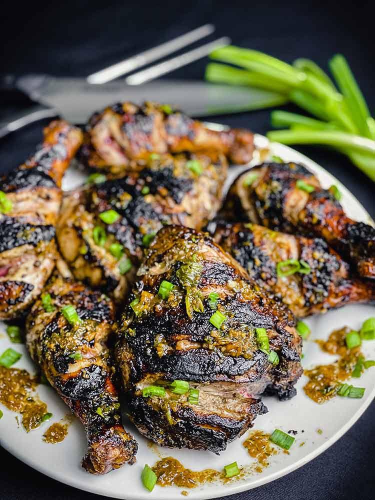 Close-up shot of jerk chicken with jalapeño peppers on a grill