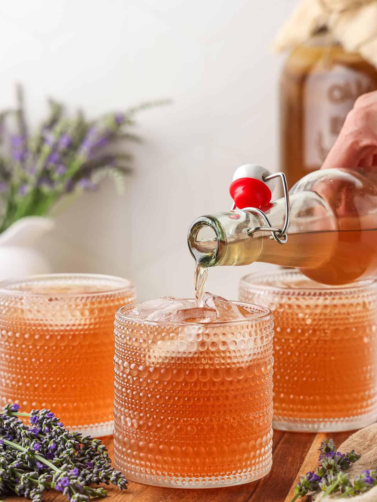 A pitcher of Lavender Kombucha Spritzer with glasses and ice next to it.