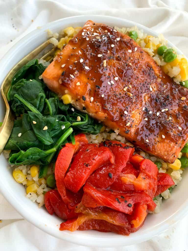 A full shot of a beautifully presented Honey Garlic Glazed Salmon Protein Bowl, with the salmon in the center and vegetables arranged artfully around it.