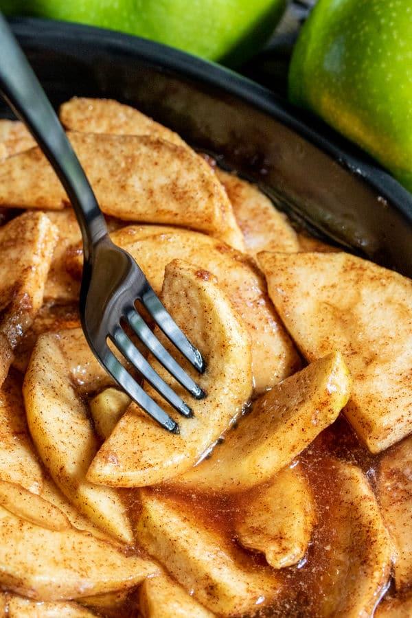 close-up of apple slices being tossed in cinnamon and sugar