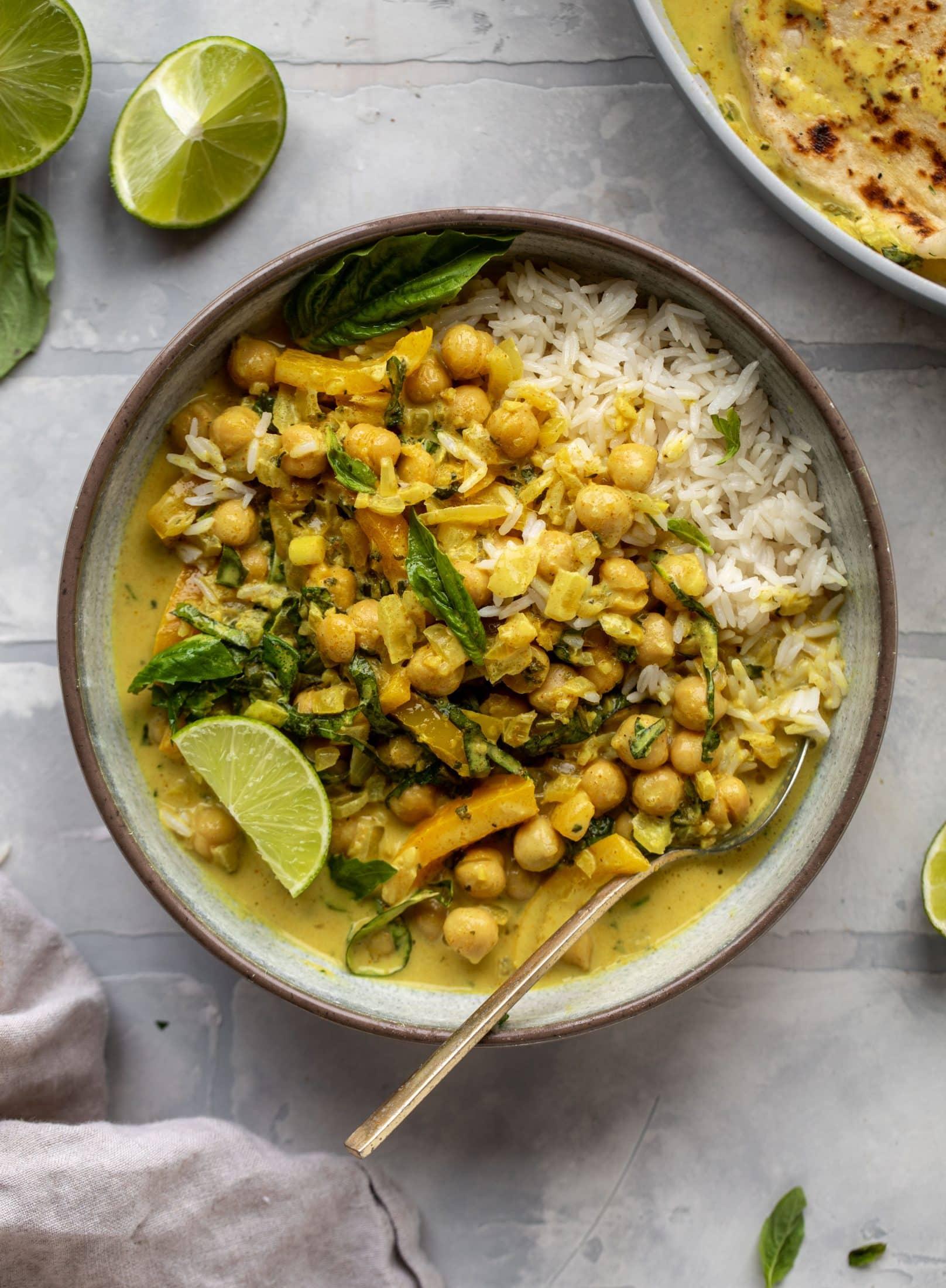 rustic bowl of chickpea and artichoke curry with a sprig of basil