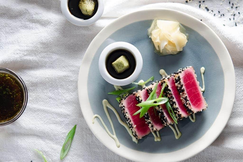 overhead shot of beautifully plated steamed fish with wasabi mayo, garnished with lemon and herbs