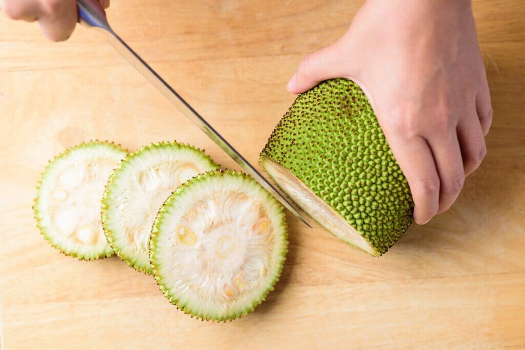 jackfruit being sliced on a cutting board