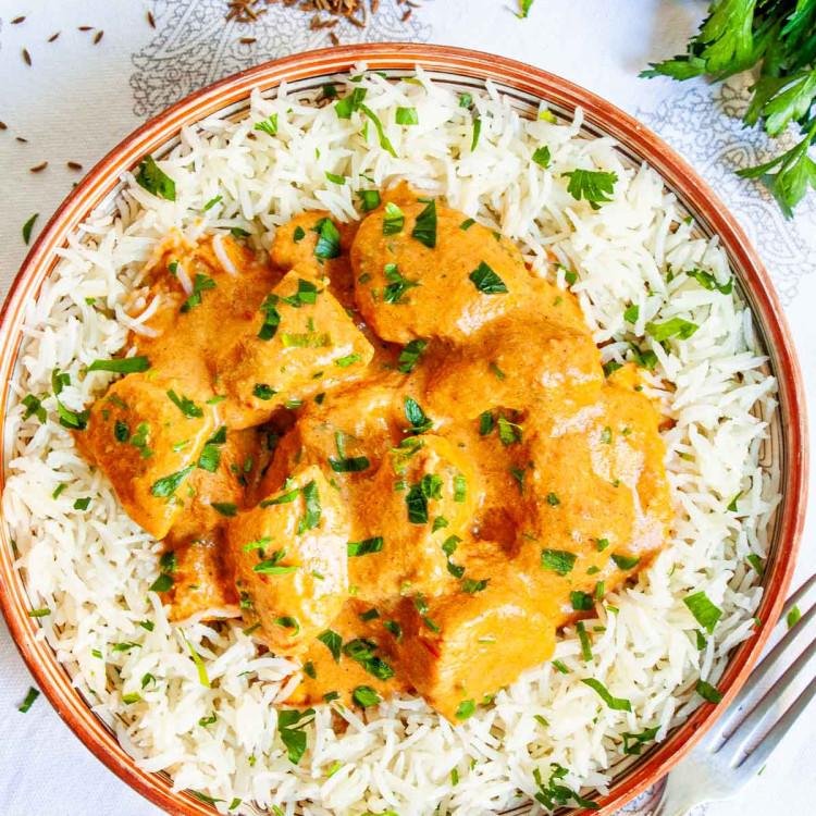 A full shot of a plate of Garlic Butter Chicken and Rice, garnished with parsley