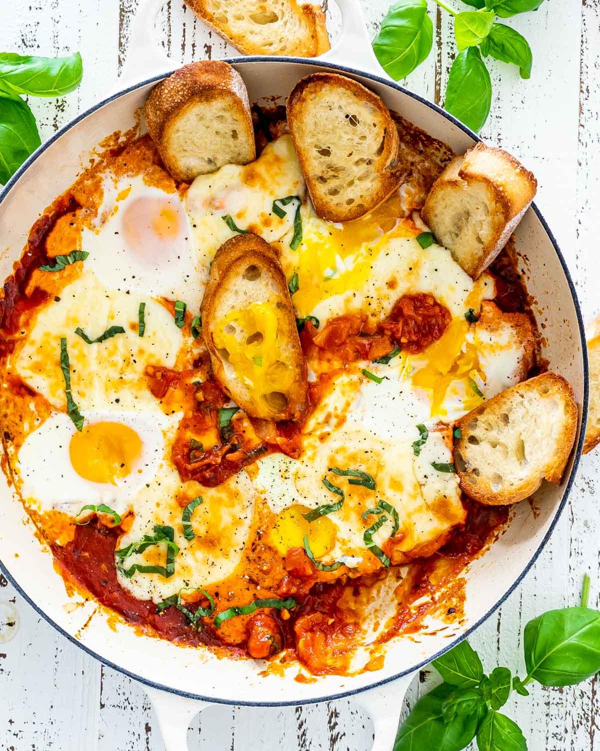 a person dipping crusty bread into Mediterranean Shakshuka