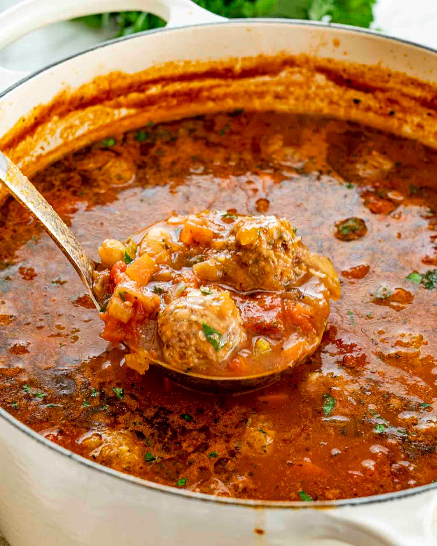 Close-up shot of the meatballs simmering in a saucepan, showing the rich broth.