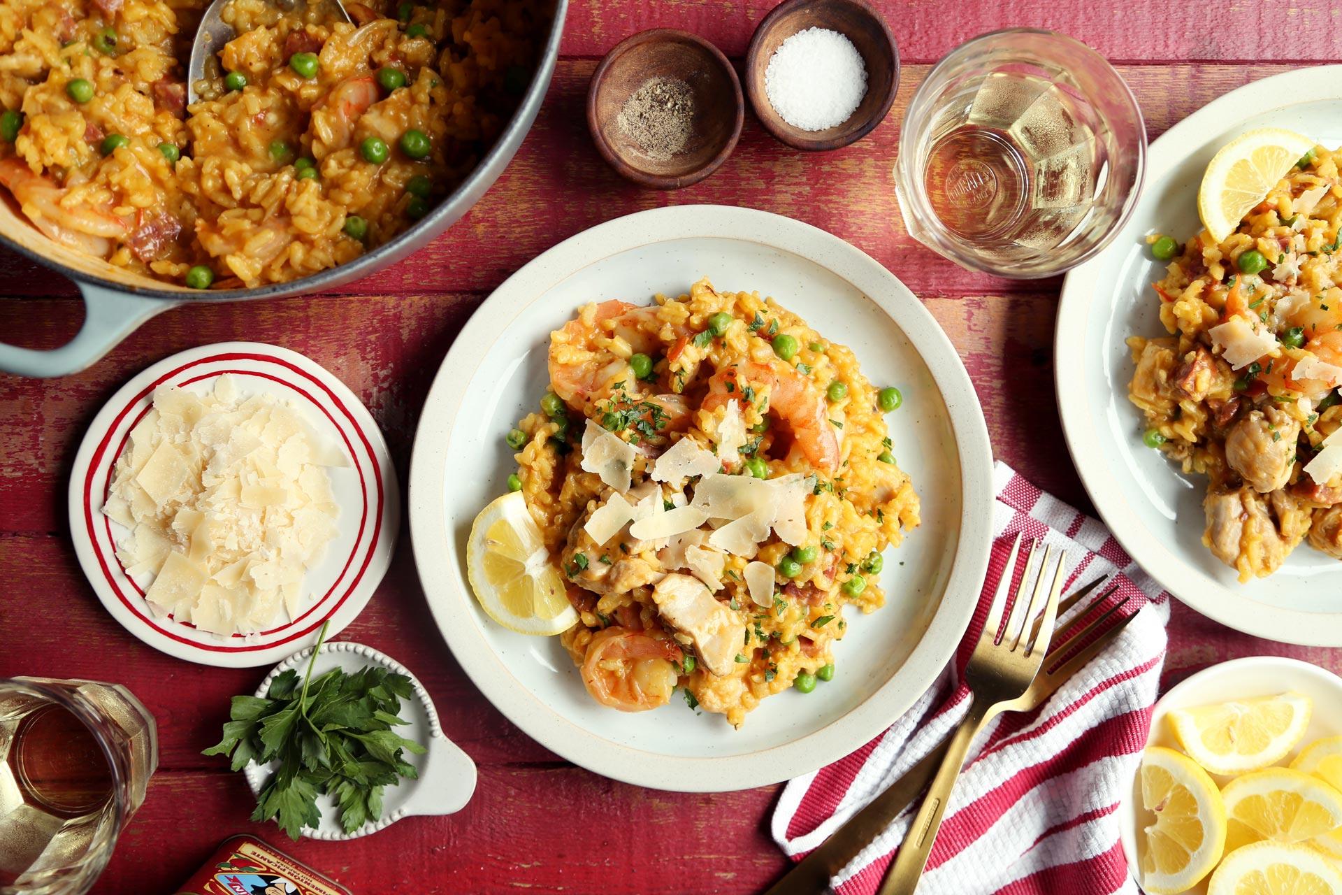 Saffron and Seafood Paella Risotto being served in a bowl, garnished with fresh parsley and a lemon wedge
