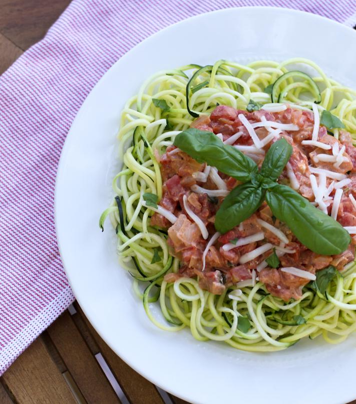 Close-up shot of a vibrant plate of zucchini noodles with creamy tomato sauce, garnished with fresh basil