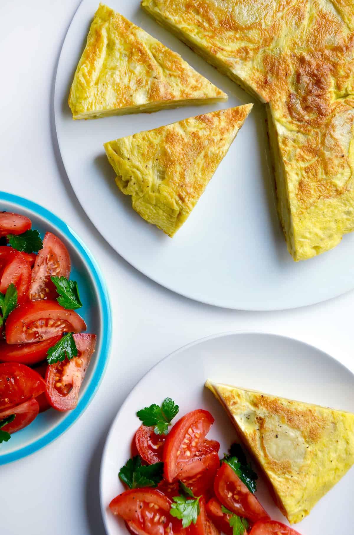 Tortilla Española cut into wedges and served on a platter with a side salad