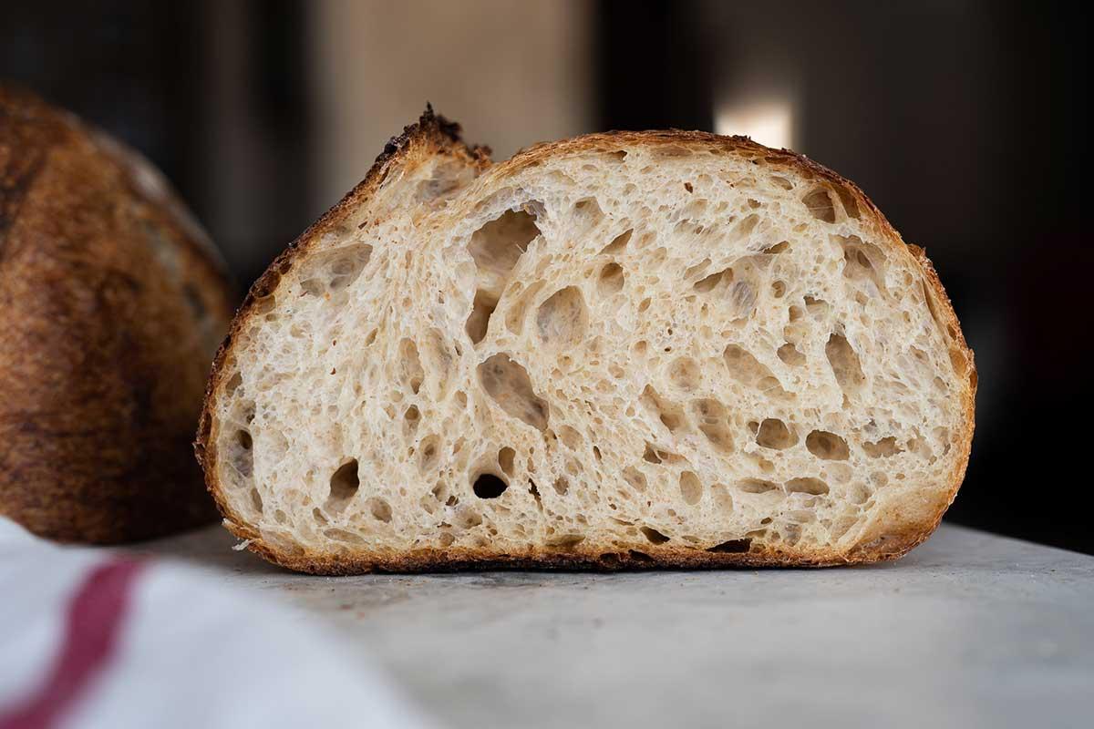 A close-up shot of a perfectly risen sourdough boule with an open crumb structure