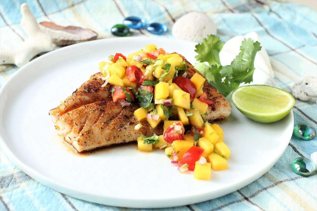 A beautifully set table with grilled fish fillets and mango salsa