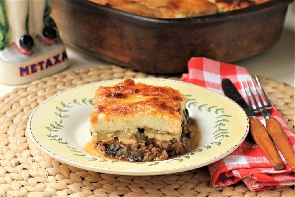 A rustic kitchen setting with a family preparing moussaka