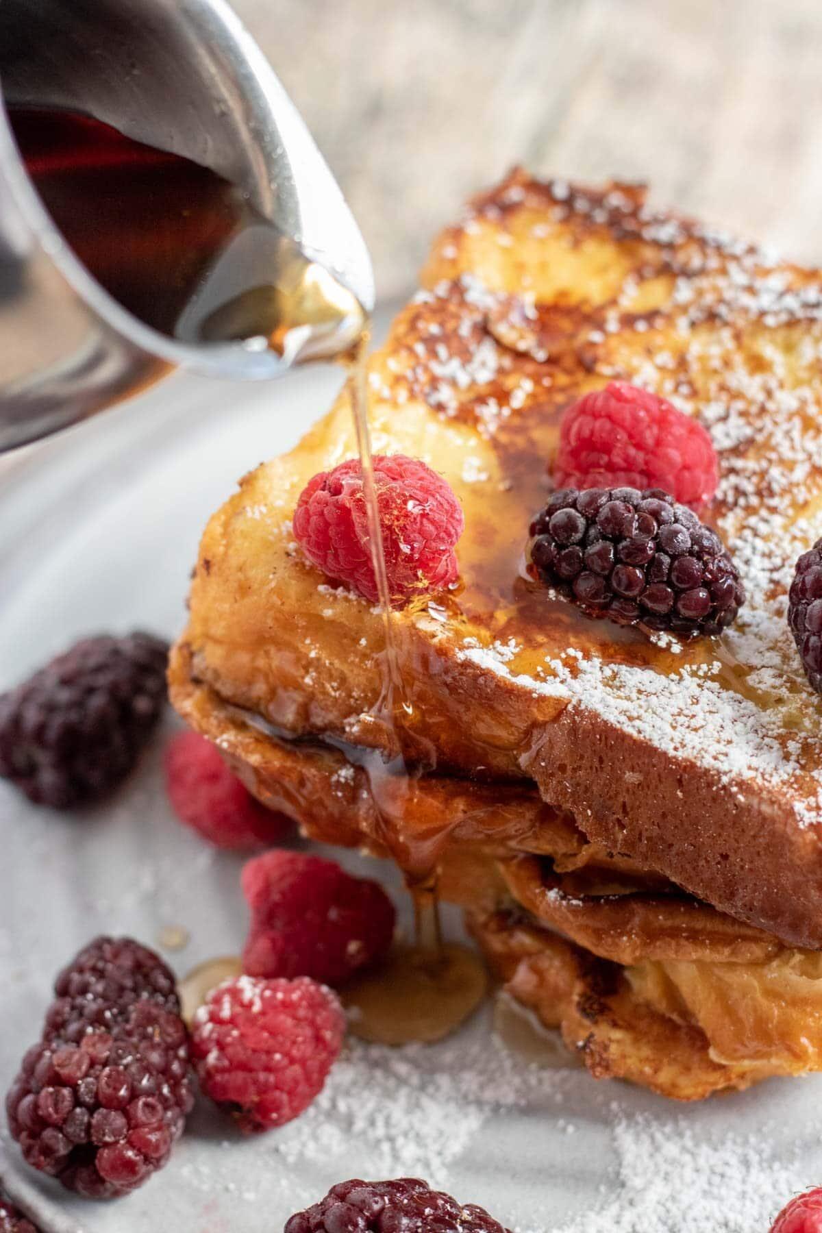 Close-up shot of golden brown Kit Kat French toast with syrup and berries