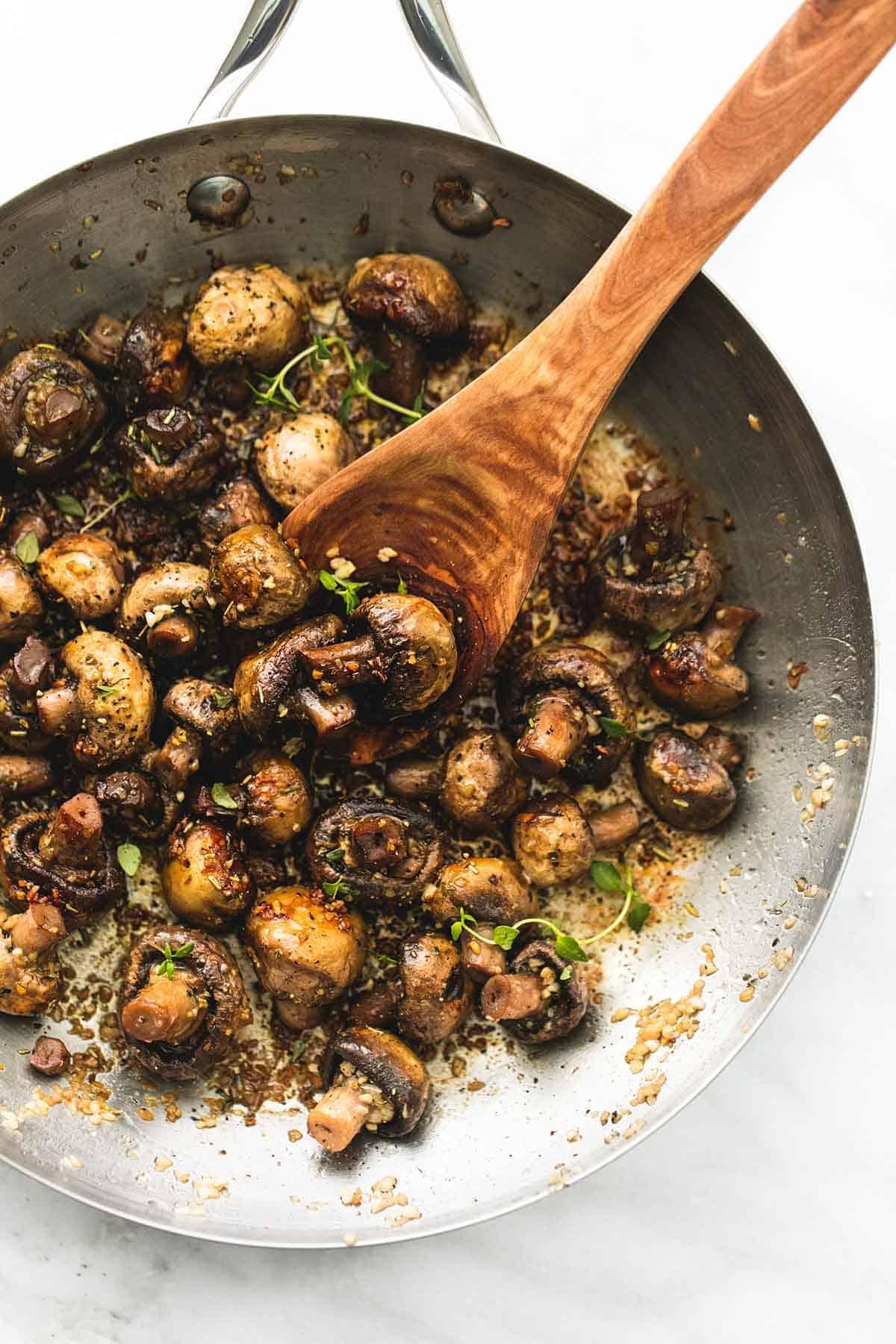 close-up shot of sautéed mushrooms sizzling in a pan with garlic and herbs