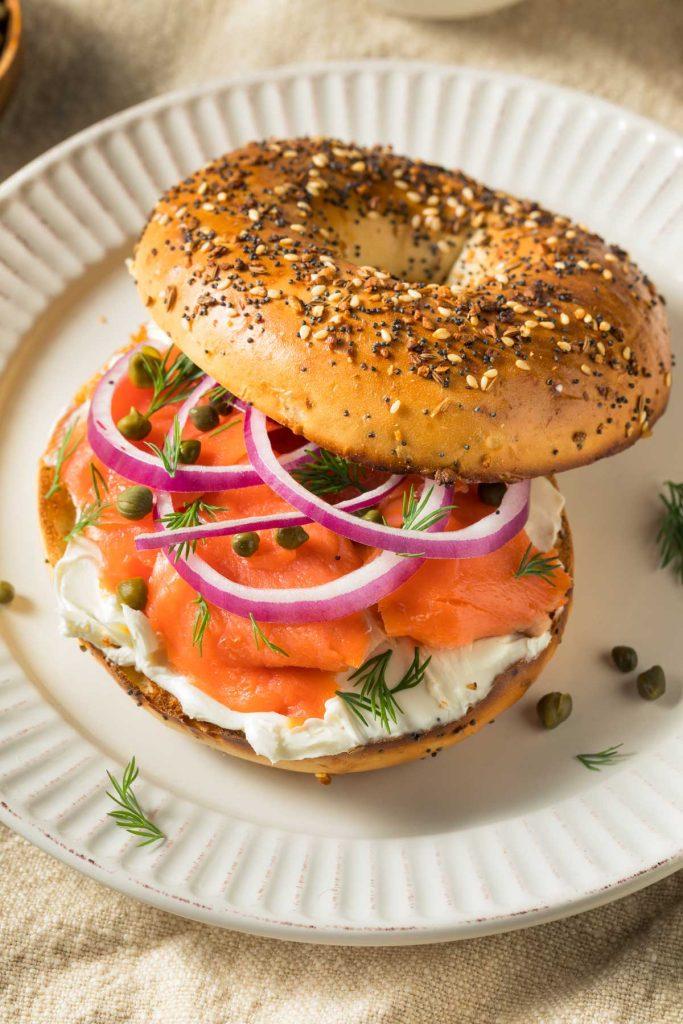 A person enjoying a poppy seed bagel with smoked salmon