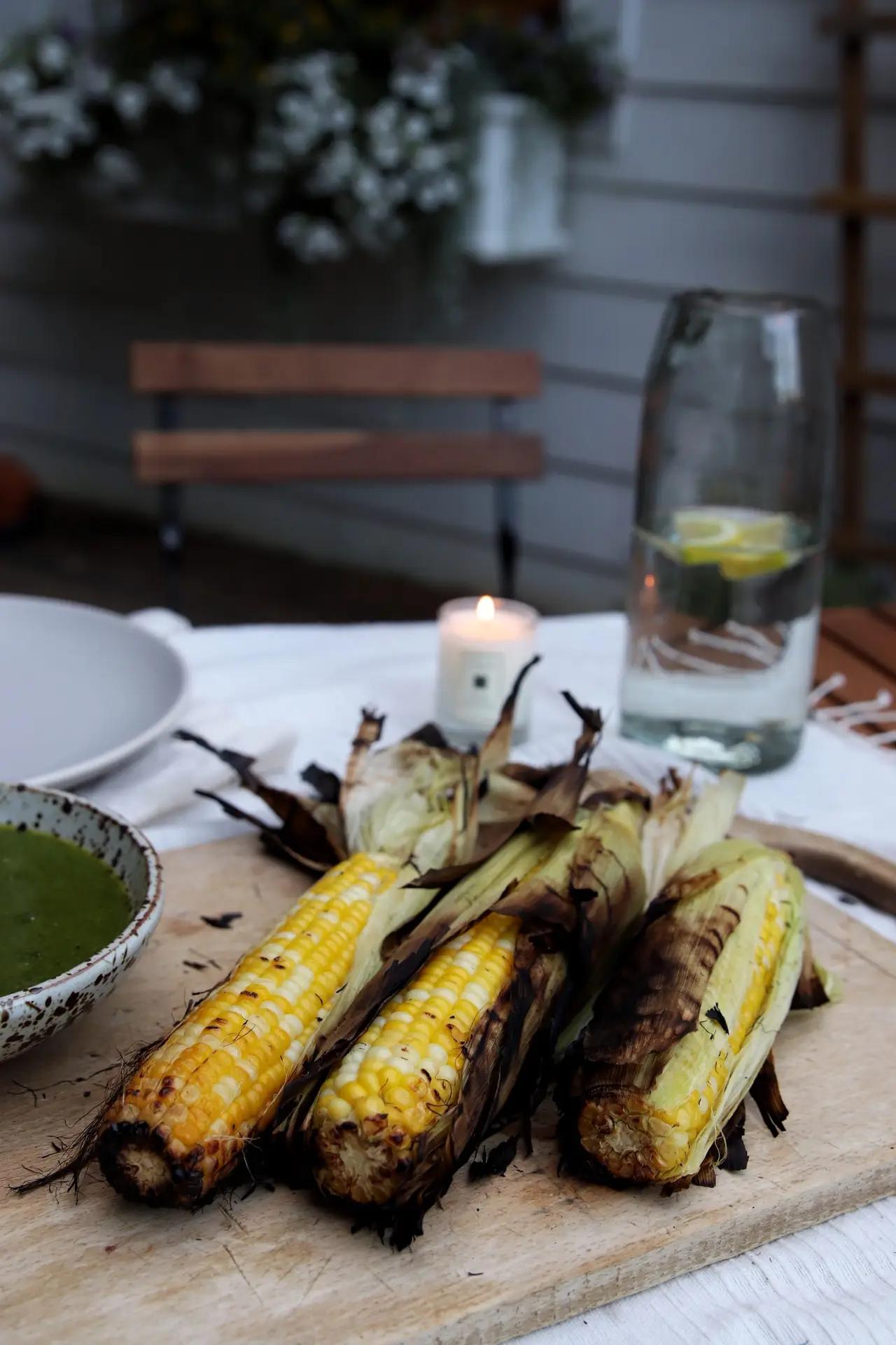 close up of grilled corn with garlic scape pesto being brushed on
