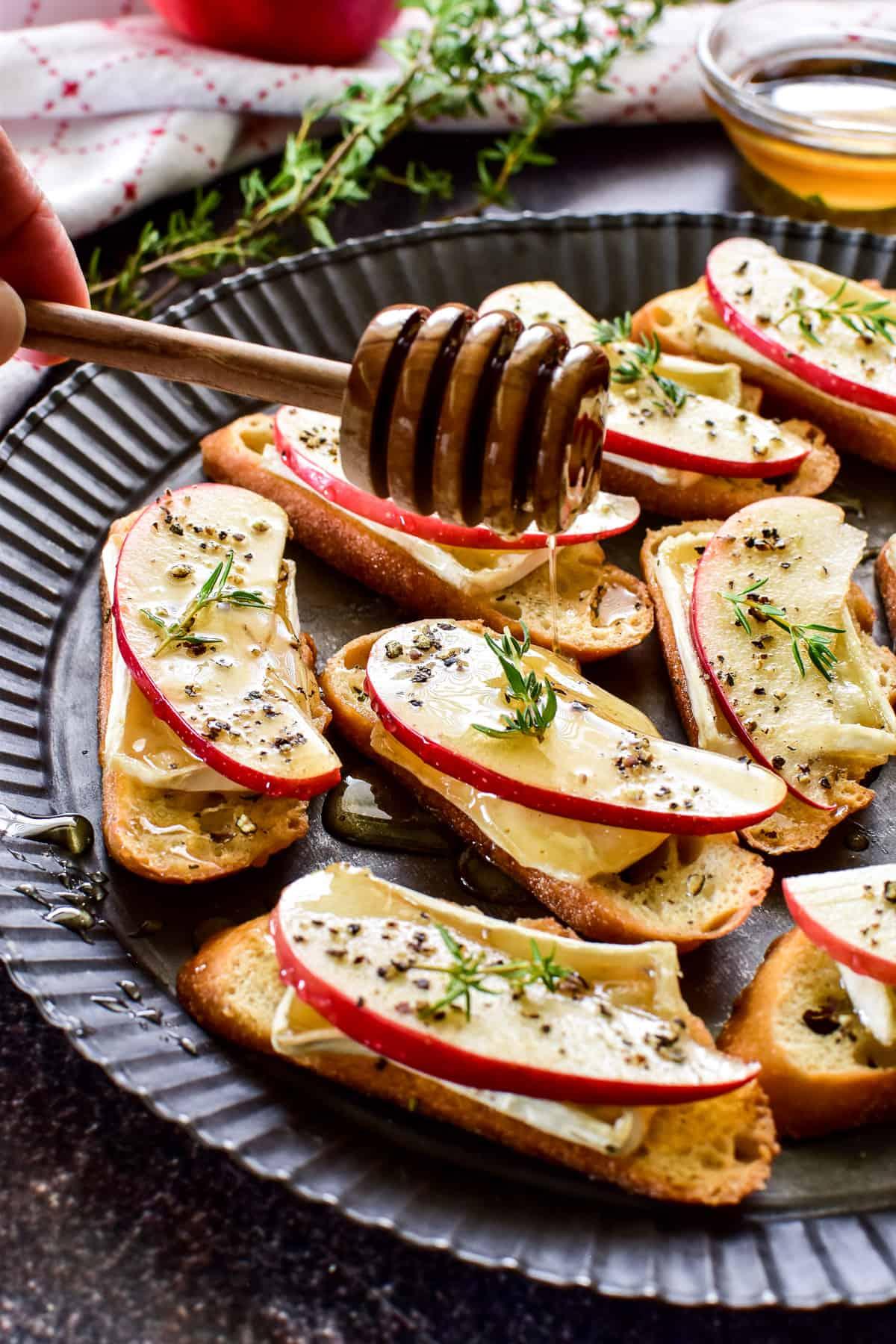 A platter of apple and brie bruschetta garnished with fresh rosemary