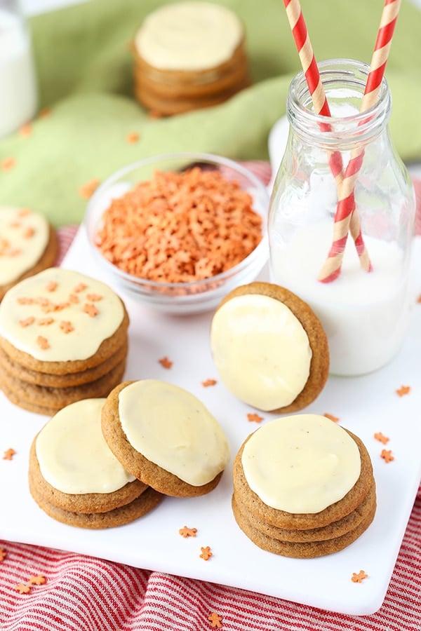 A plate of Eggnog Gingerbread Cookies with a glass of eggnog in the background