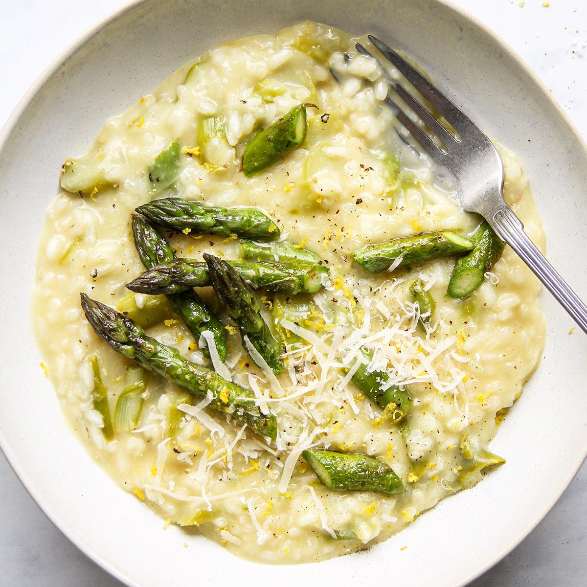 A creamy asparagus risotto with vibrant green asparagus spears and a sprinkle of red chili flakes.