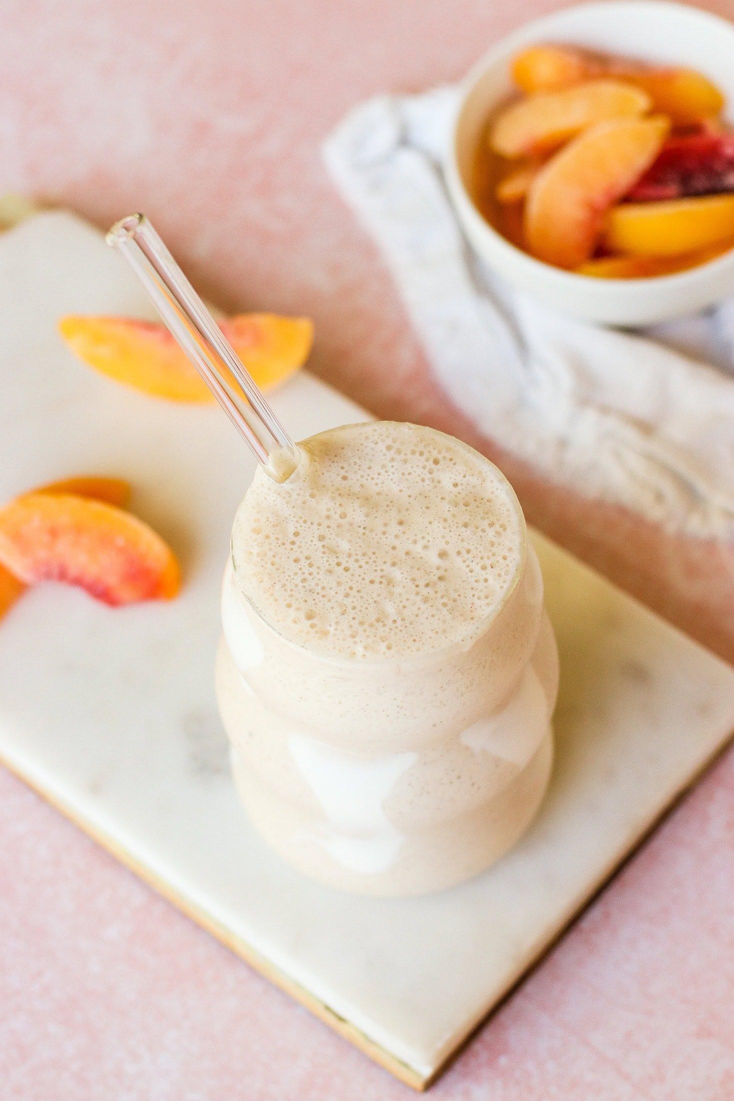 a close-up shot of a creamy vanilla peach smoothie being poured into a glass