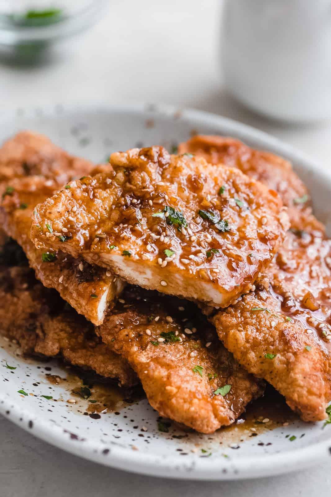 Close-up shot of crispy-skinned chicken thigh coated in sticky honey garlic butter sauce