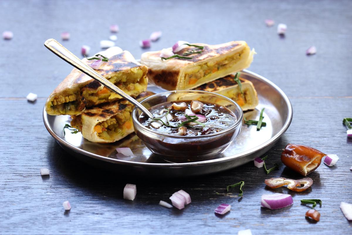 A delicious, lightly browned roti on a plate with some curry and chutney