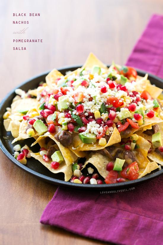 A vibrant plate of nachos topped with a glistening pomegranate sauce and various toppings.