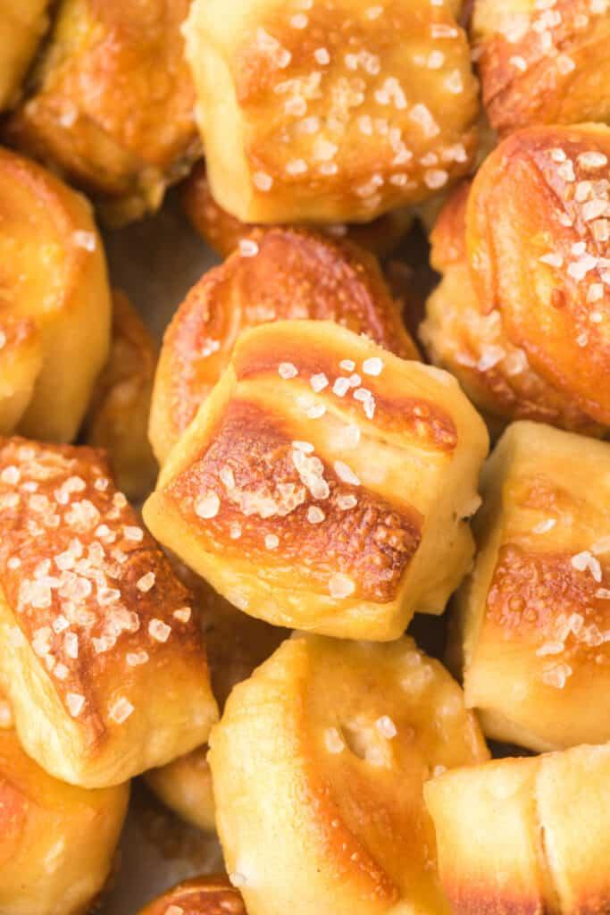 A close-up shot of golden-brown stadium pretzels arranged on a baking sheet, with a bowl of creamy ranch dip beside them. 