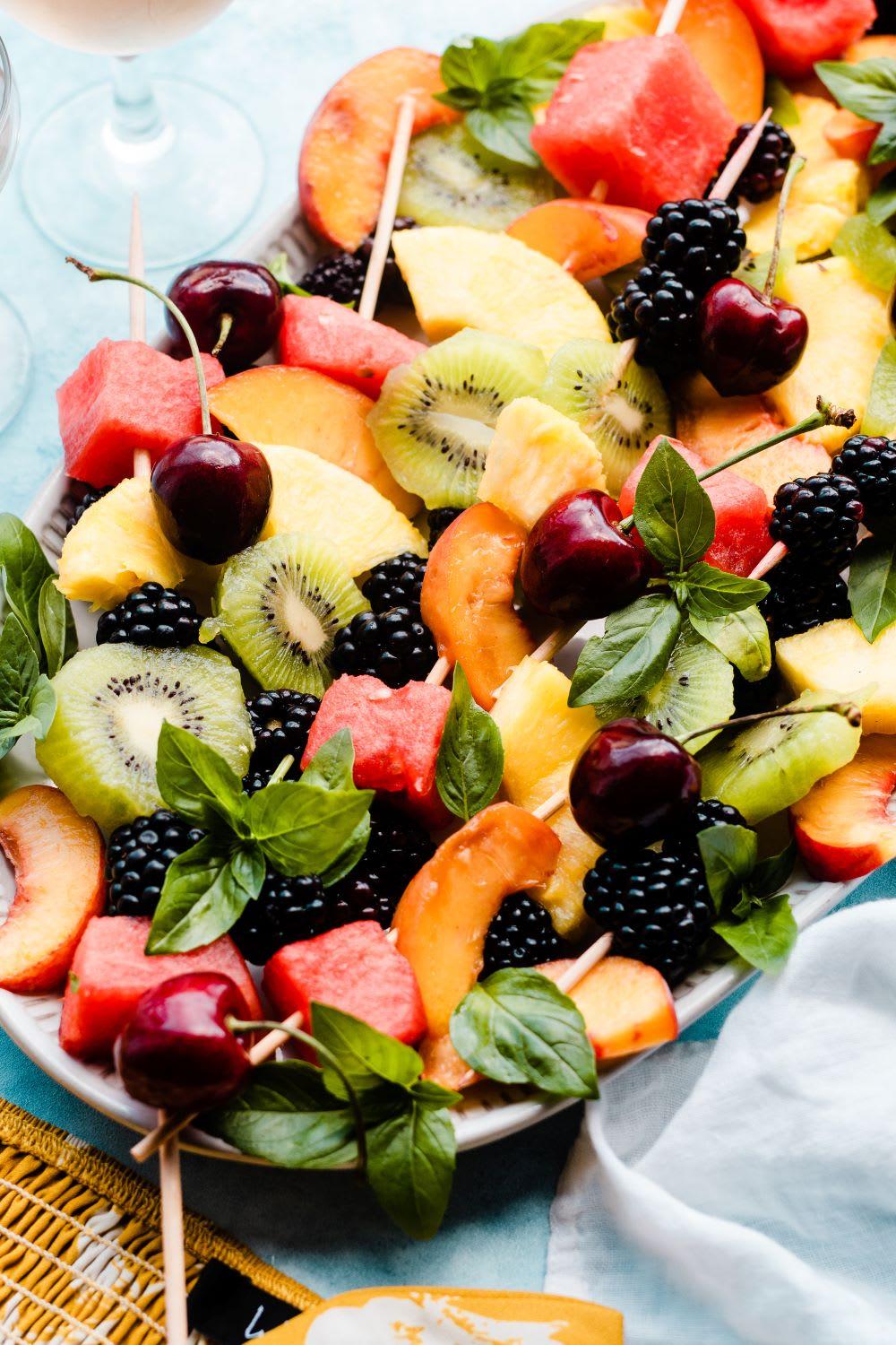 A vibrant image of a picnic with colorful fruit kebabs in the foreground