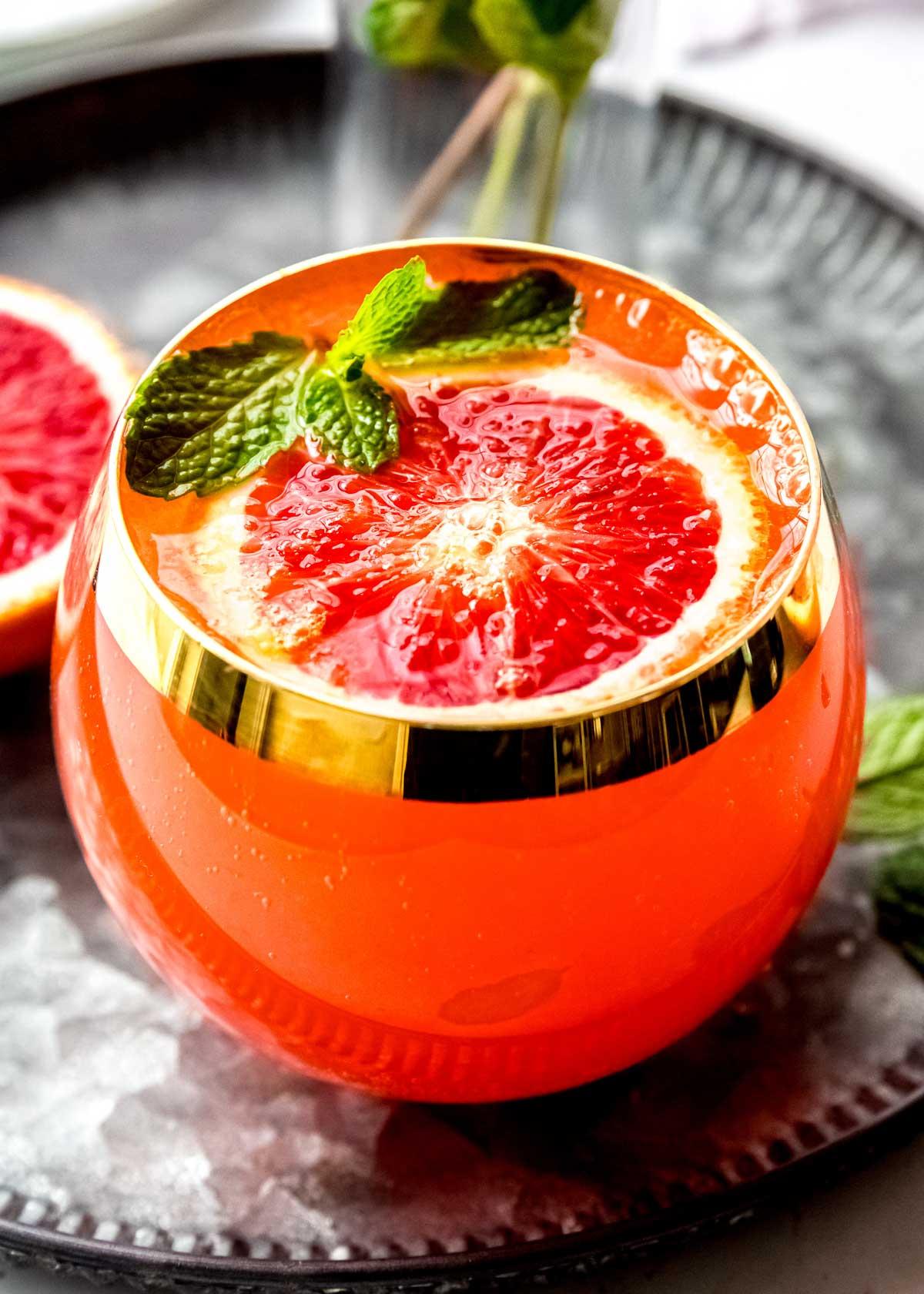 Close-up shot of a mimosa cocktail garnished with fresh orange slices and berries