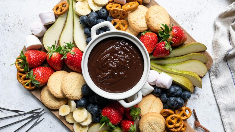 A decadent whisky chocolate fondue served in a rustic bowl with fondue forks and various dippers.