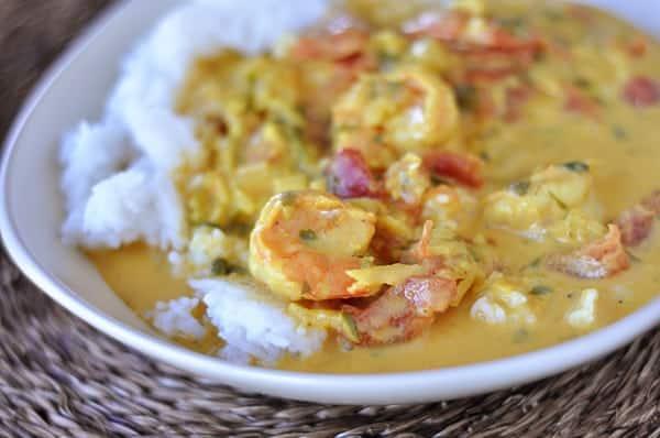close-up shot of shrimp sashimi bathed in creamy coconut curry sauce