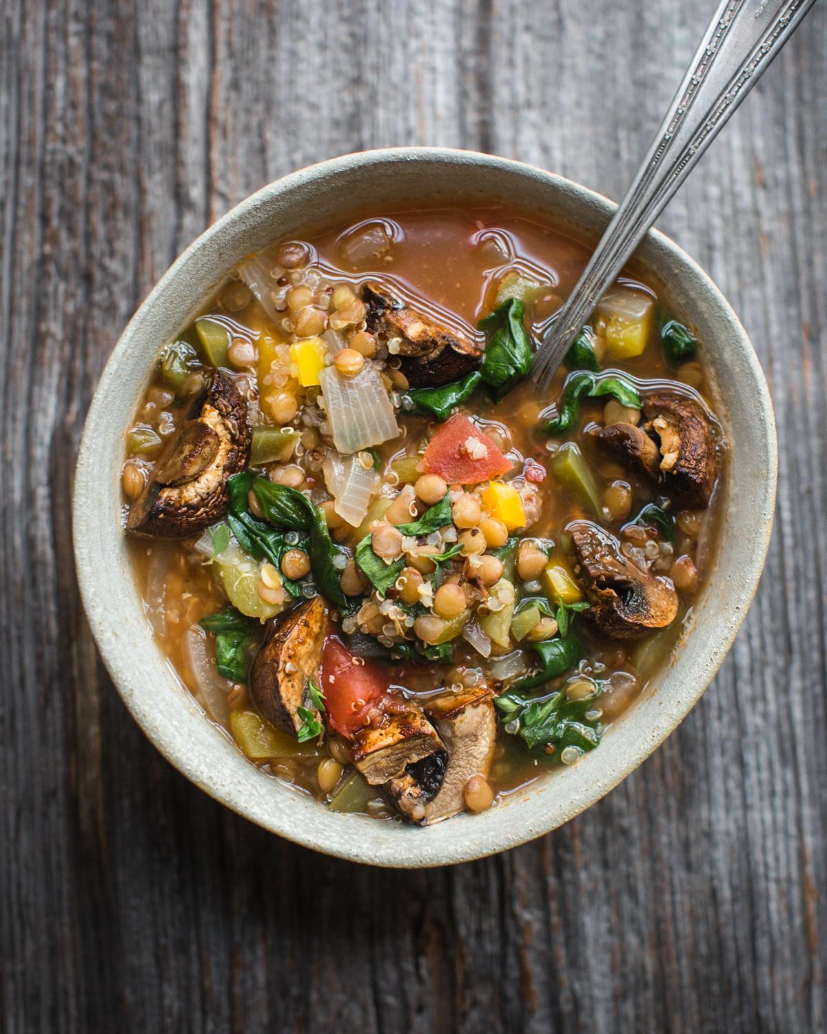 A person ladling quinoa and lentil soup into bowls