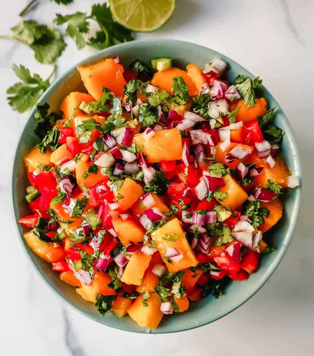 Close-up shot of a vibrant mango salsa with fresh cilantro and red onion