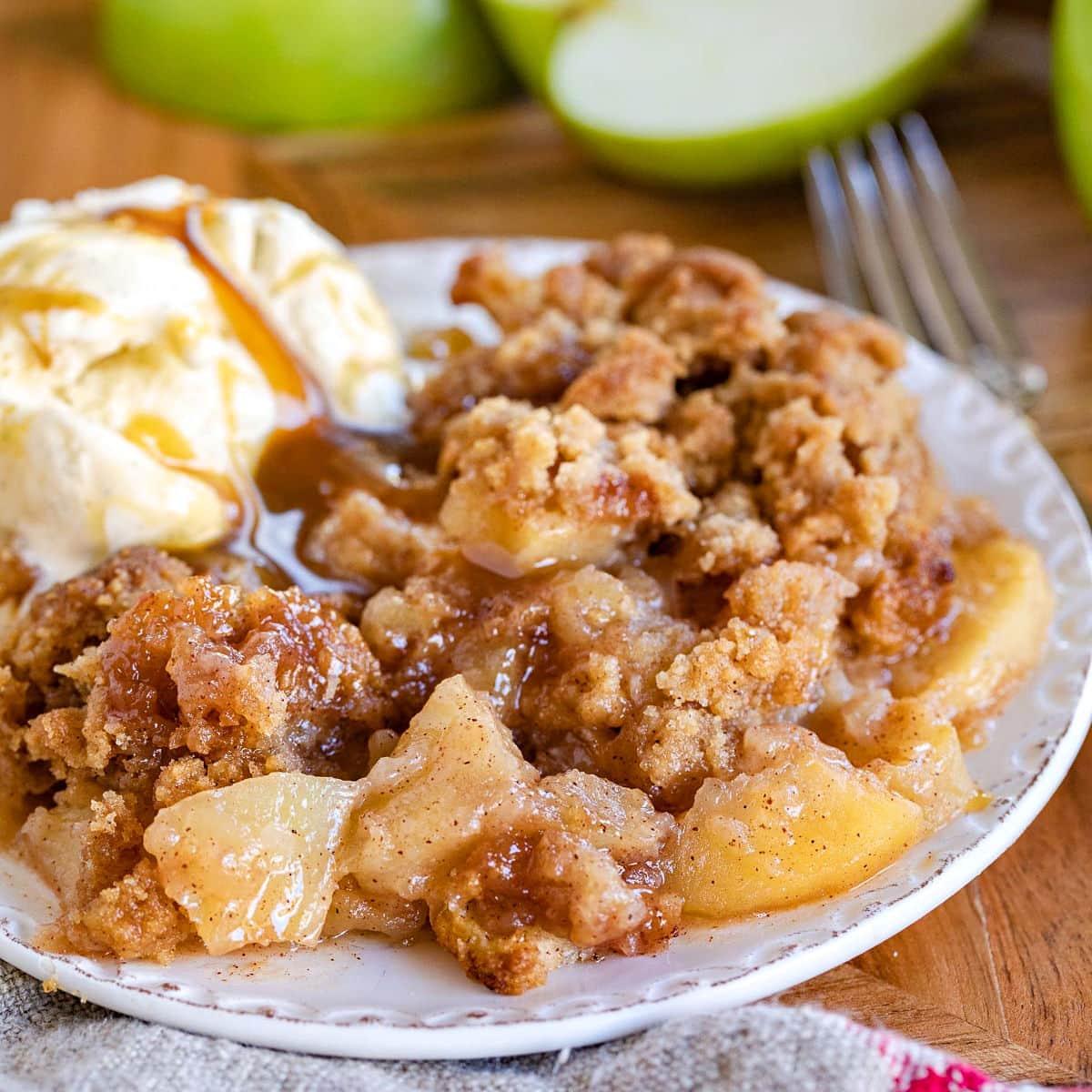 A golden-brown apple crumble with a crisp streusel topping, served warm with a scoop of vanilla ice cream